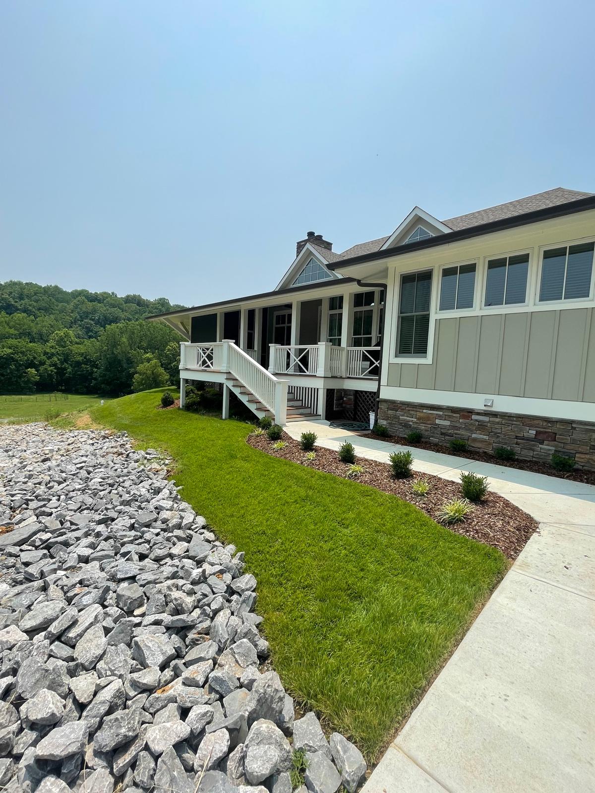 Completed residential landscaping project with stone accents, professional lawn care, and decorative rock features